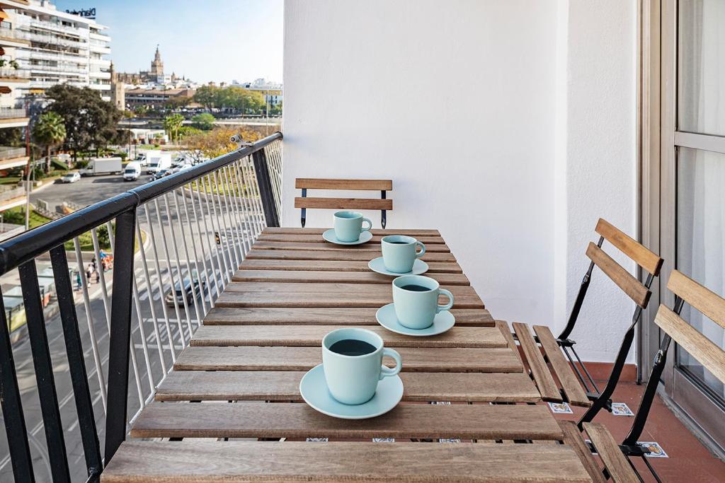 einen Tisch mit Tassen und Untertassen auf einem Balkon in der Unterkunft AlohaMundi Plaza de Cuba in Sevilla