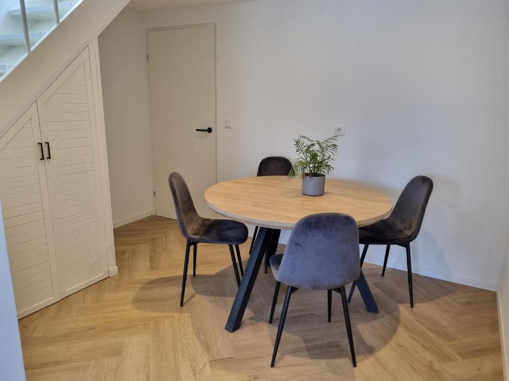 a dining room table with four chairs and a potted plant at Calm Down Near The Sea in Vlissingen