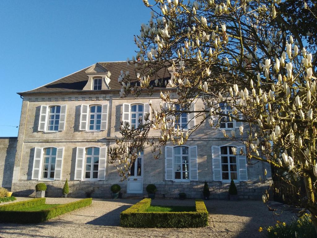 a large stone house with white windows and a tree at Charme D Antan in Villers-Châtel