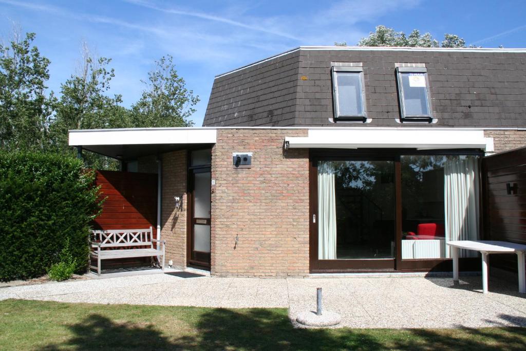 een stenen huis met een bank ervoor bij Liguster 8 in Nieuwvliet