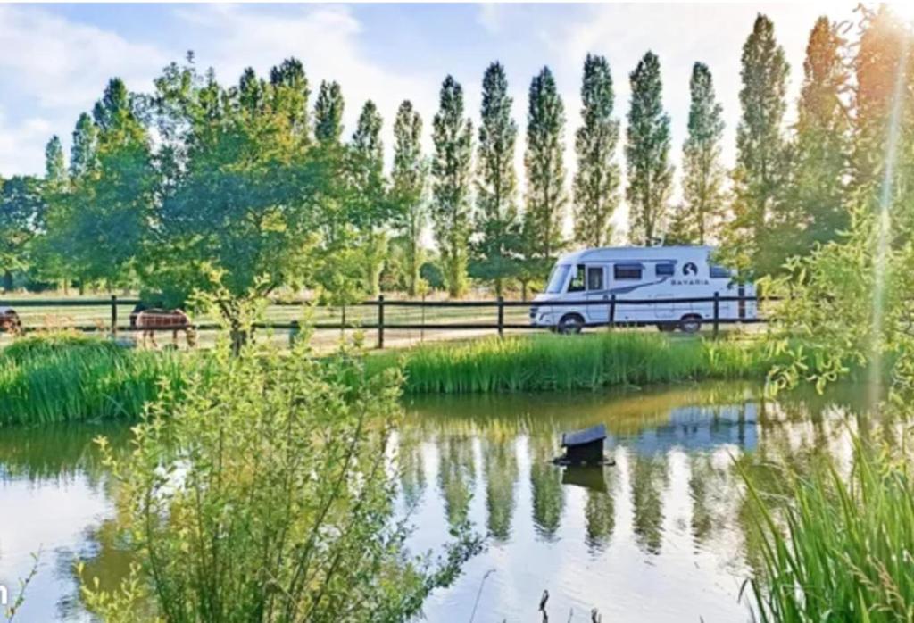 un wagon garé à côté d'un lac avec un canard dans l'eau dans l'établissement Le Pressoir de Gisay Camping Car et Caravane Uniquement, à Gisay