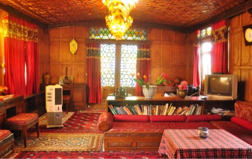 Alif Laila Group of Houseboats, Srinagar في سريناغار: غرفة معيشة مع أريكة حمراء وستائر حمراء