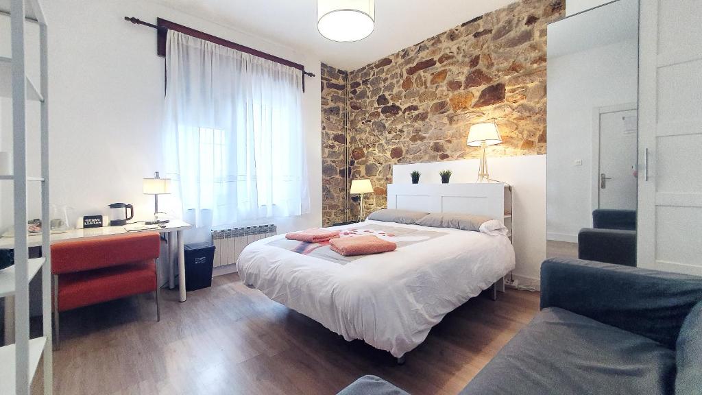 1 dormitorio con cama y pared de piedra en 2-TUUL ETXEA, Habitación doble a 8 km de Bilbao, Baño compartido, en Galdakao