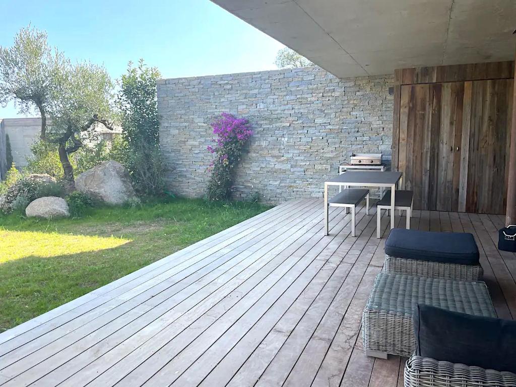 a wooden deck with a table and chairs on it at Appartements Les Lofts de Sainte-Lucie-de-Porto-Vecchio in Sainte-Lucie de Porto-Vecchio