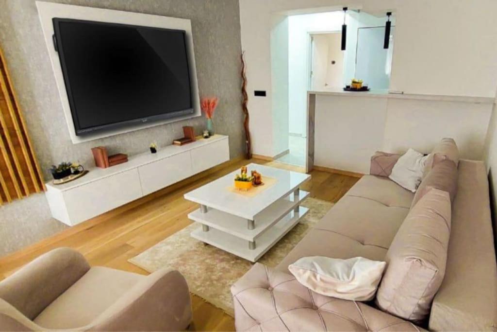 uma sala de estar com um sofá e uma televisão de ecrã plano em The Modern Lodge em Skopje