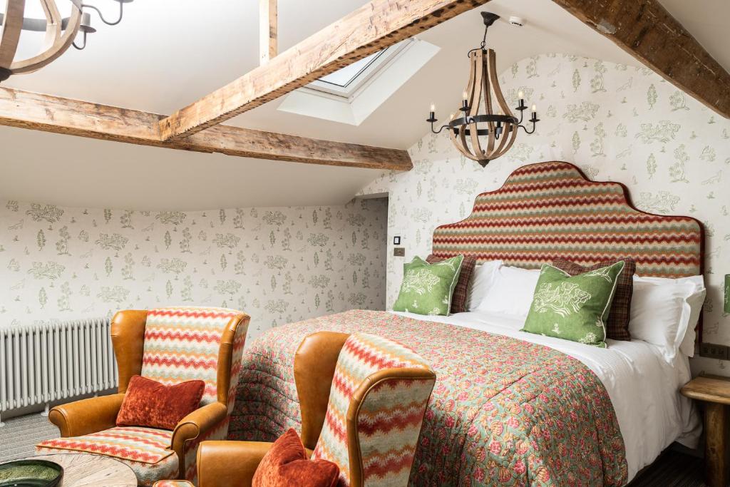 a bedroom with a large bed and two chairs at The Dalesman Country Inn in Sedbergh