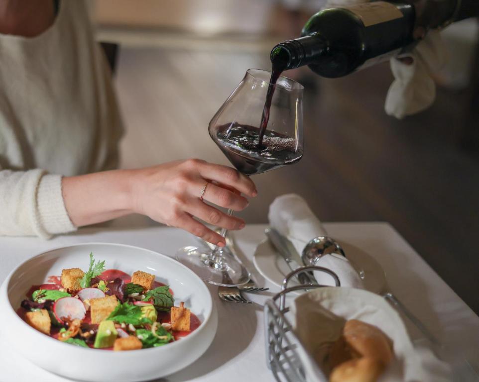 a person pouring a glass of wine into a bowl of food at Zanzibar White Sand Luxury Villas & Spa - Relais & Chateaux in Paje