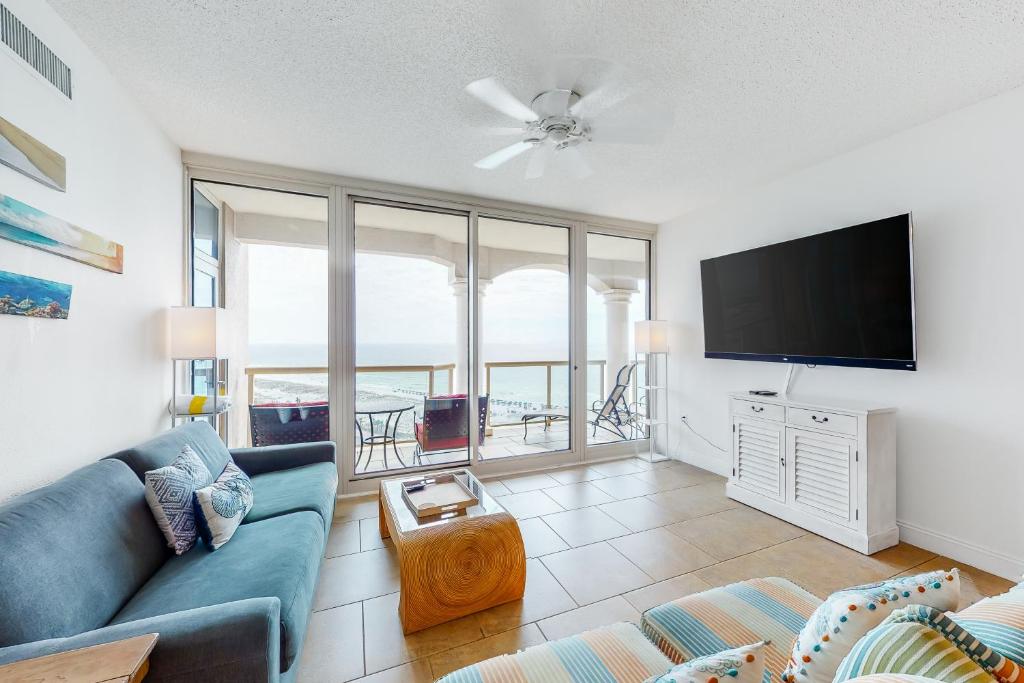 sala de estar con sofá azul y TV de pantalla plana en Portofino Island Resort and Spa Tower One 1108, en Pensacola Beach