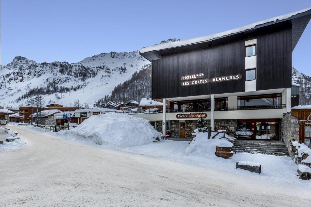 a building with snow in front of a mountain at Les Crêtes Blanches in Val dʼIsère