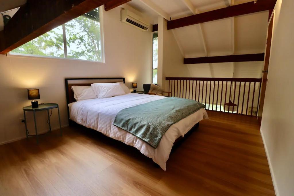 a bedroom with a bed and a large window at Maleny-Montville Cottages in Balmoral Ridge