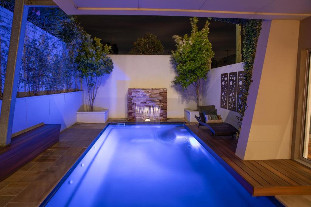 een zwembad in een achtertuin 's nachts met blauwe verlichting bij Luxurious Terrace Hideaway with a Heated Pool in Ocean Grove