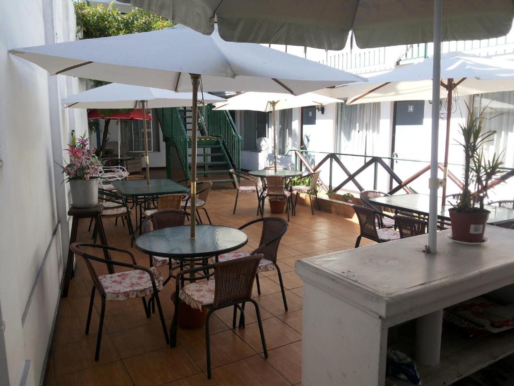 un patio con mesas, sillas y sombrillas en Residencial Las Palmeras, en Iquique