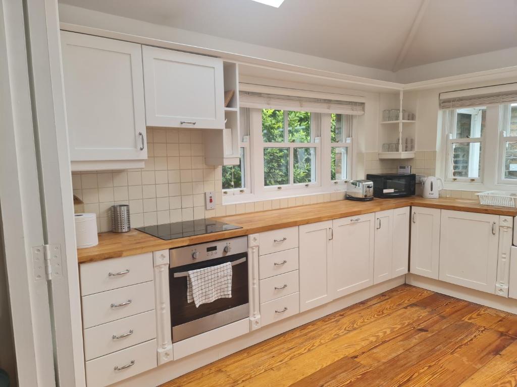 a kitchen with white cabinets and wooden floors at Central Prime King Size Apartment in Dublin