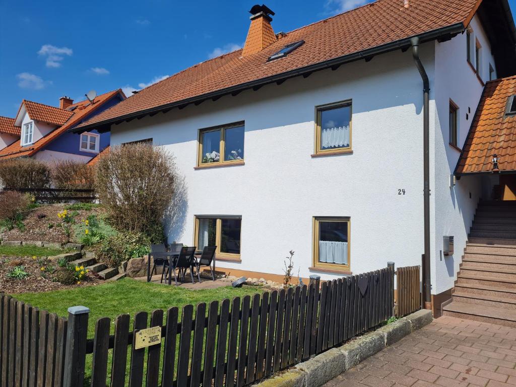 a white house with a wooden fence at Ferienwohnung Chrissi in Bischofsheim an der Rhön