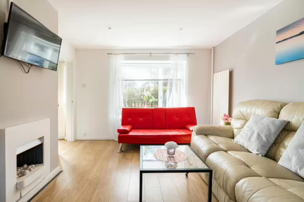 uma sala de estar com um sofá e uma cadeira vermelha em Stevenage Contractors x8 New 3 bedroom House Free Wifi, Parking, Towels all inclusive & Large Garden em Stevenage