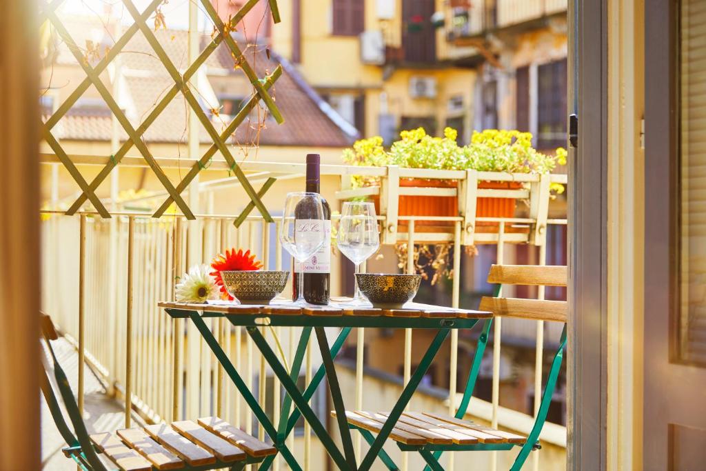 uma mesa com copos de vinho e plantas numa varanda em House Naviglio Grande 15 minutes to duomo em Milão