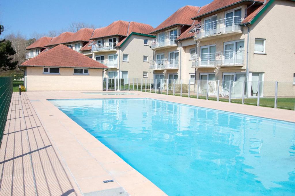 a swimming pool in front of some apartment buildings at Holiday Suites De Haan in De Haan