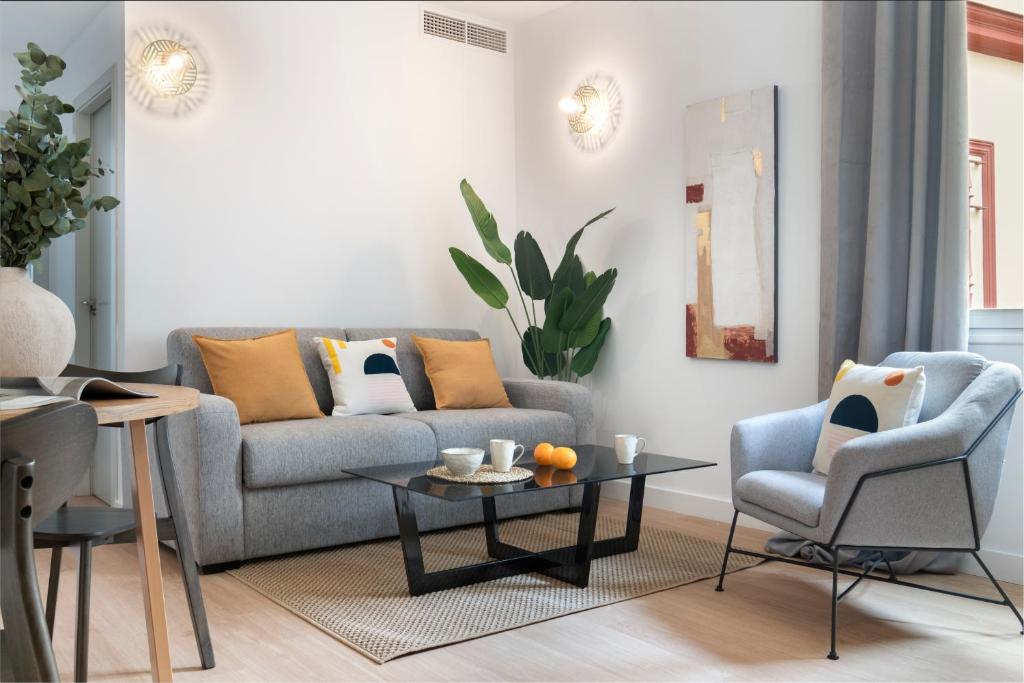 sala de estar con sofá, mesa y sillas en Suites Maestranza - Santas Patronas by Magno Apartments, en Sevilla