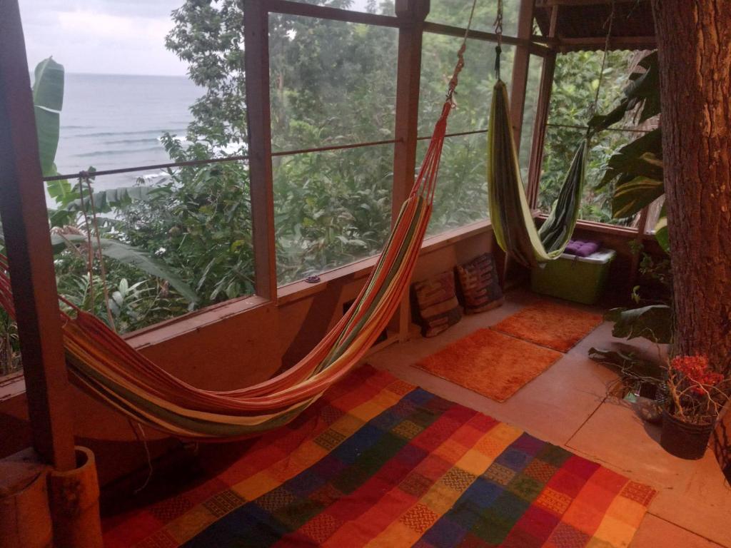 a room with two hammocks in front of a window at treehouse above the beach in Port Antonio
