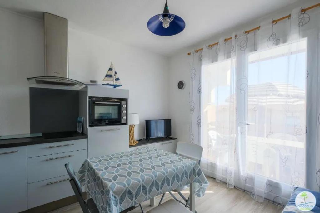 une cuisine avec une table, une télévision et une fenêtre dans l'établissement Biscarrosse Plage -T2 classé 1 étoile 3 couchages, à Biscarrosse