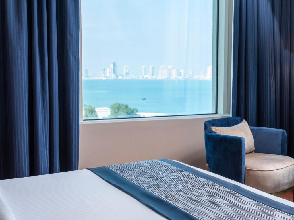 فندق رتاج الريان في الدوحة: غرفة نوم بسرير وكرسي ونافذة