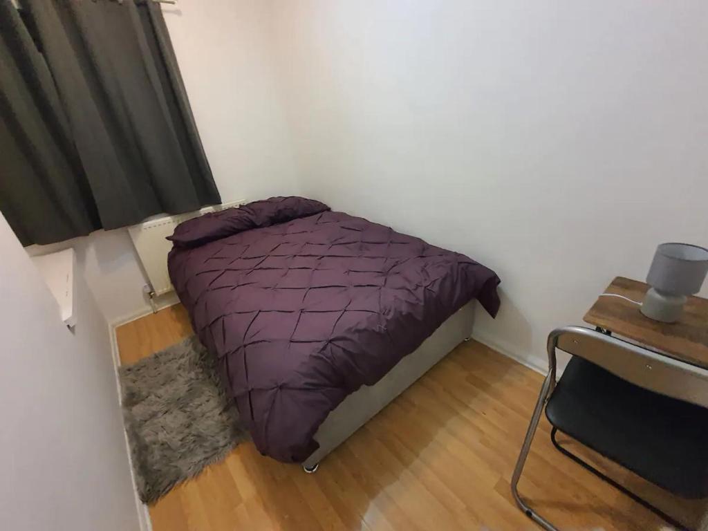 米德頓的住宿－Double Bedroom Greater Manchester，一间小卧室,配有一张紫色的床和一张桌子