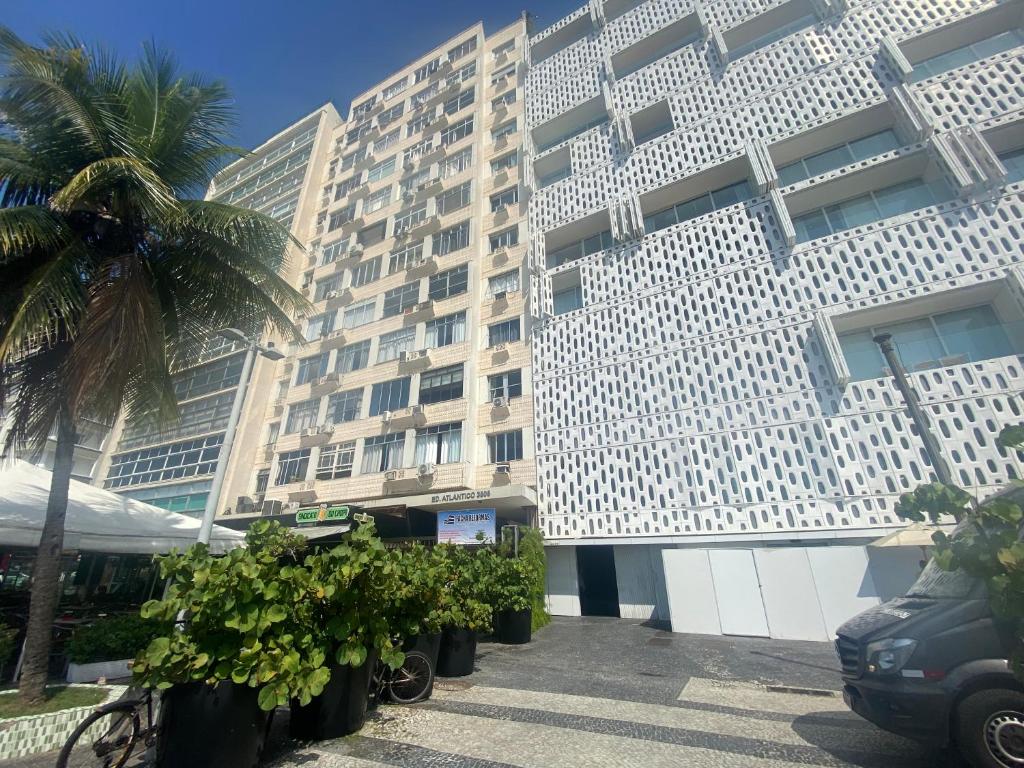 um grande edifício branco com uma palmeira ao lado em Studio completo ENTRADA pela PRAIA DE COPACABANA, com ar, wifi, netflix, até 4 pessoas, pauloangerami AA3806 em Copacabana