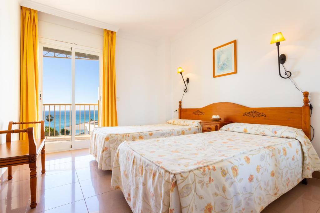 a bedroom with two beds and a large window at Apartamentos Solset Nerja in Nerja