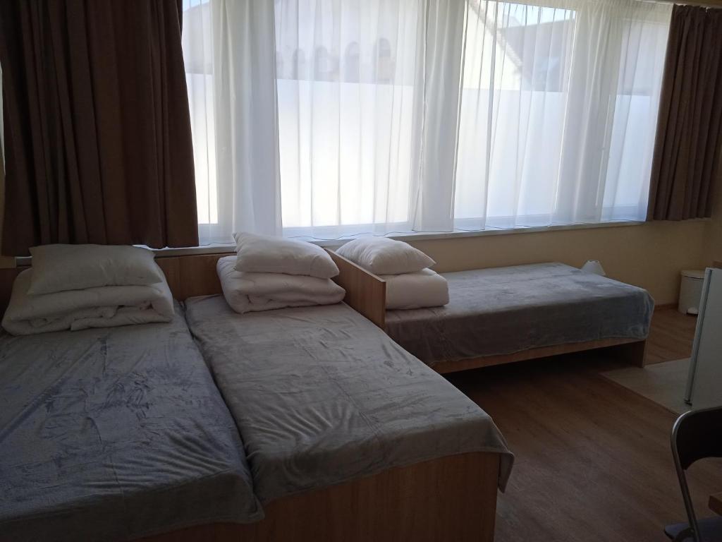 a hotel room with two beds and a window at Belvárosi Otthon Eger- Munkásszálló in Eger