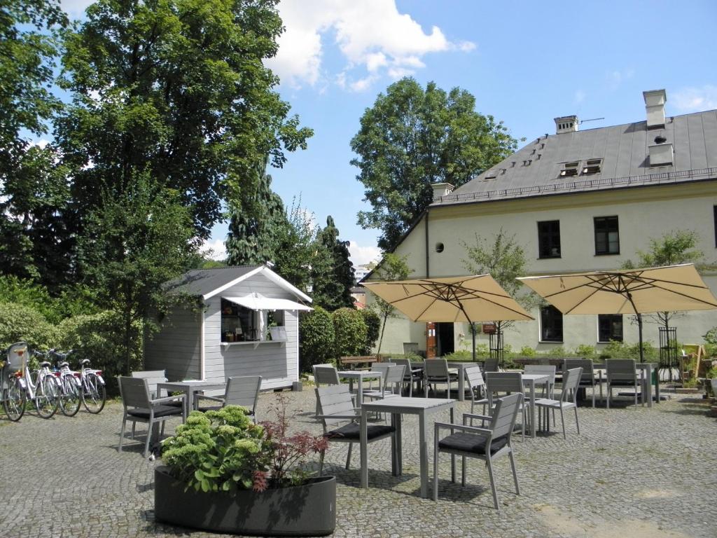 a group of tables and chairs with umbrellas next to a building at 8pokoi OFKA in Cieszyn