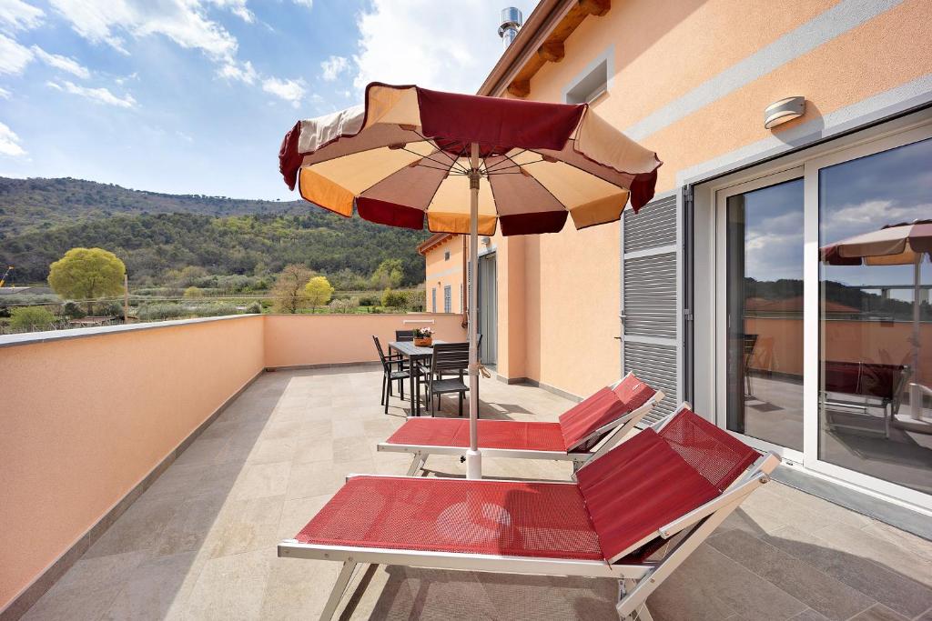 ein Balkon mit Tisch und Stühlen und einem Sonnenschirm in der Unterkunft Antichi Ricordi - Le Giare in Molino Nuovo