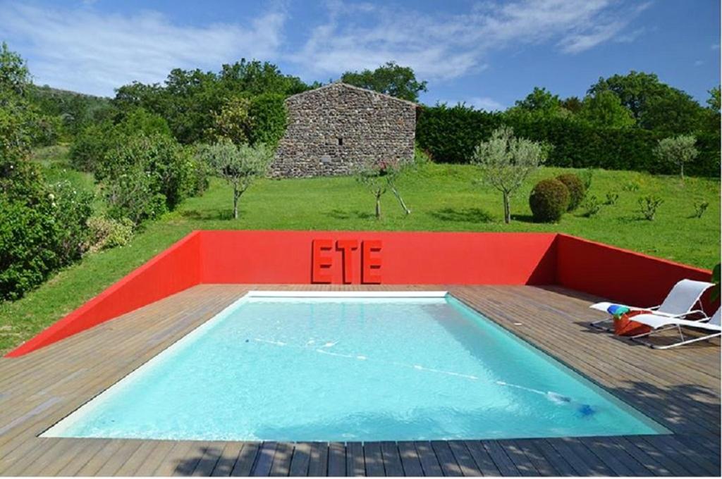 a swimming pool on a wooden deck next to a house at Maison spacieuse avec piscine à Saint-Lager-Bressac in Saint-Lager-Bressac