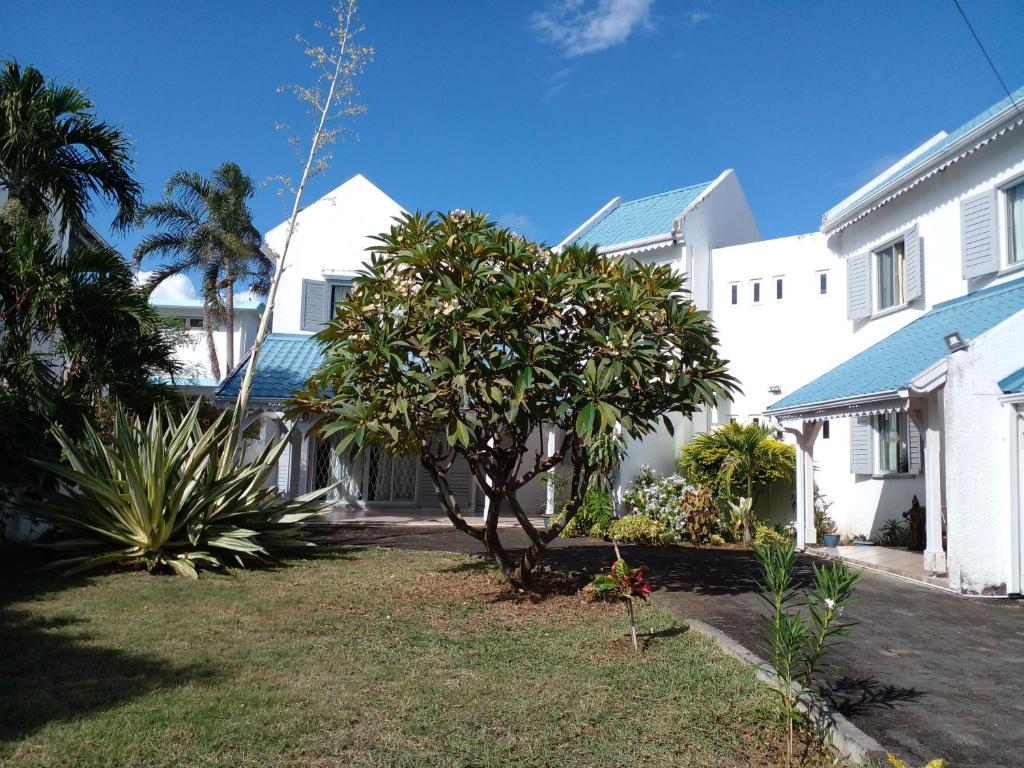 a white house with a tree in the yard at Turquoise in Blue Bay