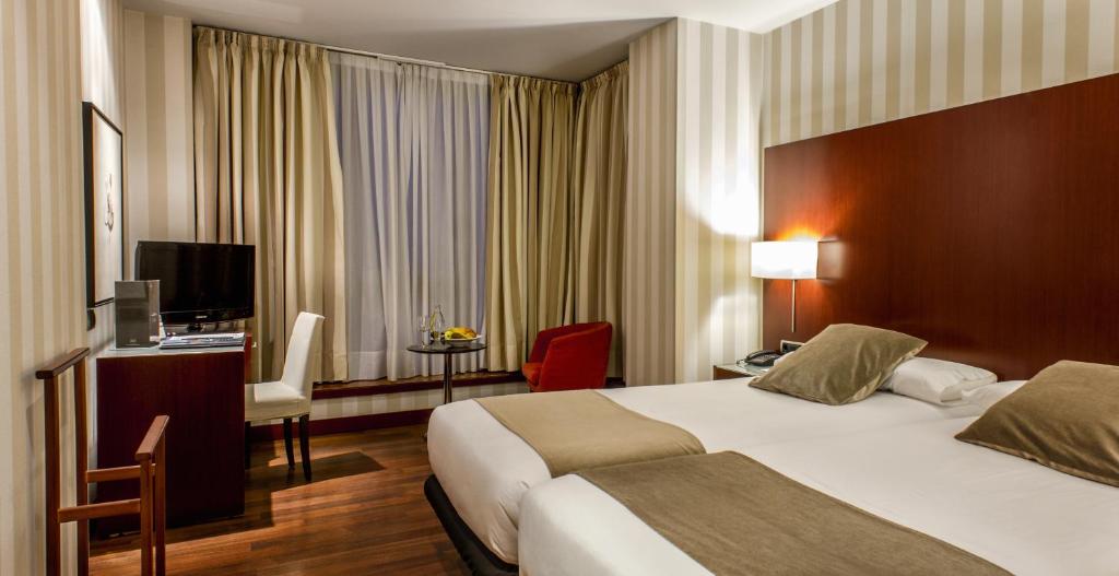 a hotel room with two beds and a television at Zenit Borrell in Barcelona