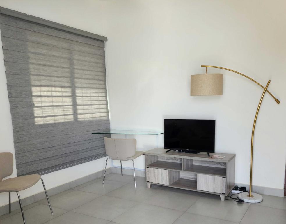 a living room with a television and a table and chairs at SBJ Place East Legon in Accra