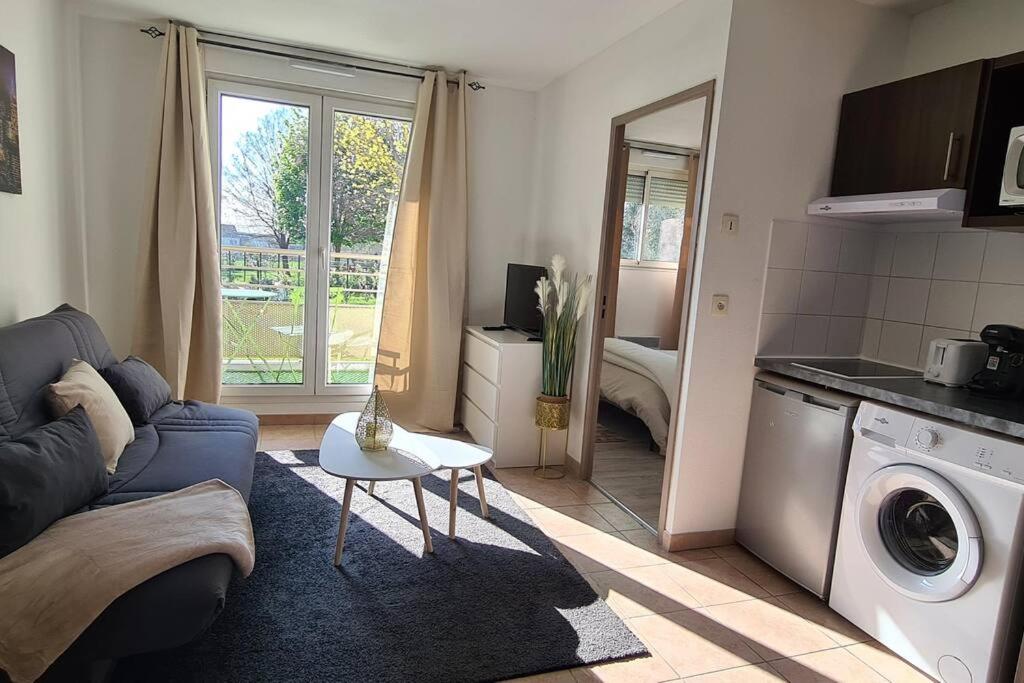 a living room with a couch and a washing machine at Appartement 10 MIN de Disneyland Paris in Montévrain