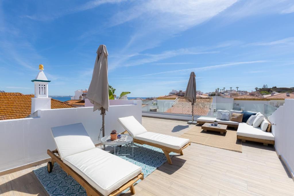 una terraza en la azotea con muebles blancos y vistas al océano. en Indigo Guest House, en Lagos