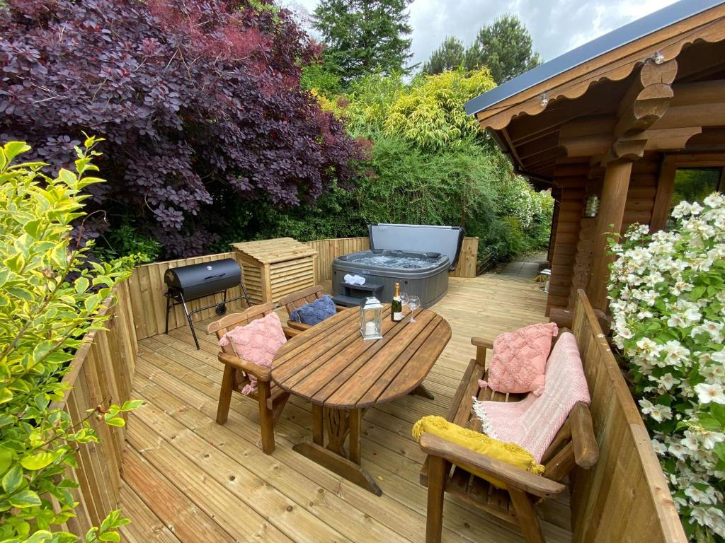 una terraza de madera con mesa, sillas y parrilla en Beautiful 2 Bedroom Log Cabin With Private Hot Tub - Elm, en Leominster