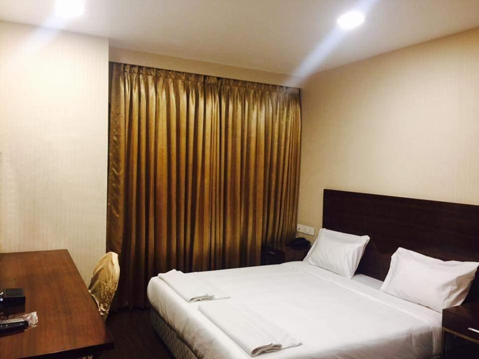 a bedroom with a bed and a desk and a window at Layalee Grande Hotel Chennai in Chennai