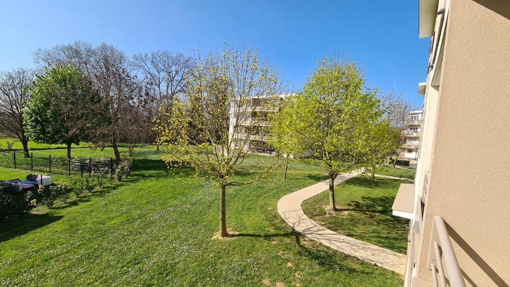 ścieżka w parku z drzewami i budynek w obiekcie C016 Appartement 10 MIN de Disneyland Paris w mieście Montévrain