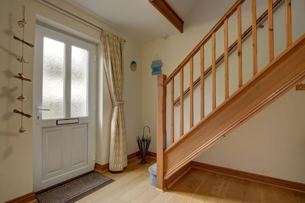 a hallway with a white door and a window at Bakers Yard in Wells next the Sea