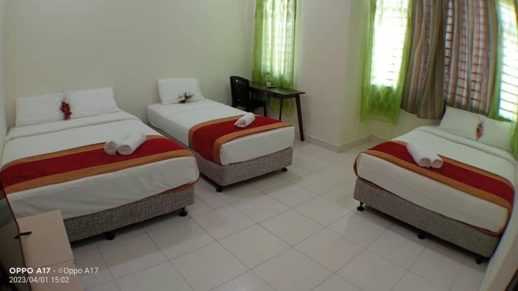 a room with three beds and a table and windows at Anggerik Heights Homestay in Bentong