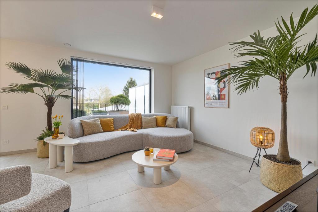 a living room with a couch and two palm trees at Flat Walnes in Diksmuide