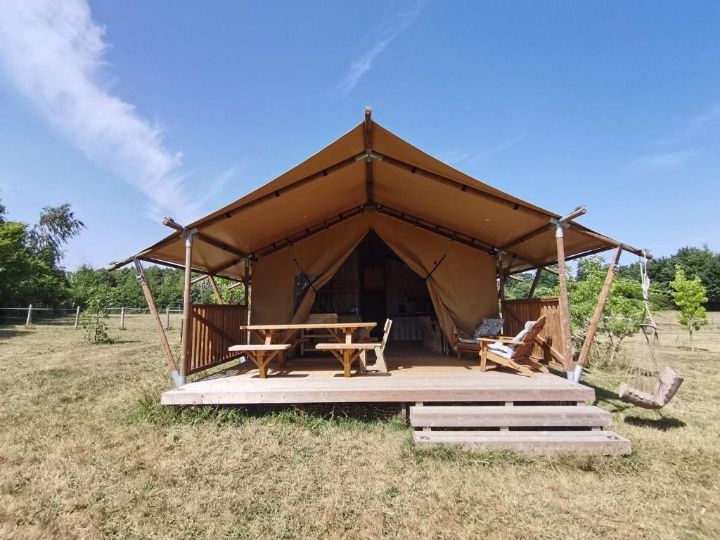 a large tent with a picnic table in a field at Tente Lodge 13 couchages in Vaas