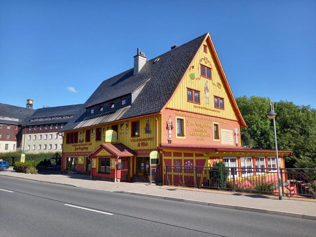 ein großes gelbes und rotes Gebäude auf der Straßenseite in der Unterkunft Pension Zum Erzgebirge in Kurort Altenberg