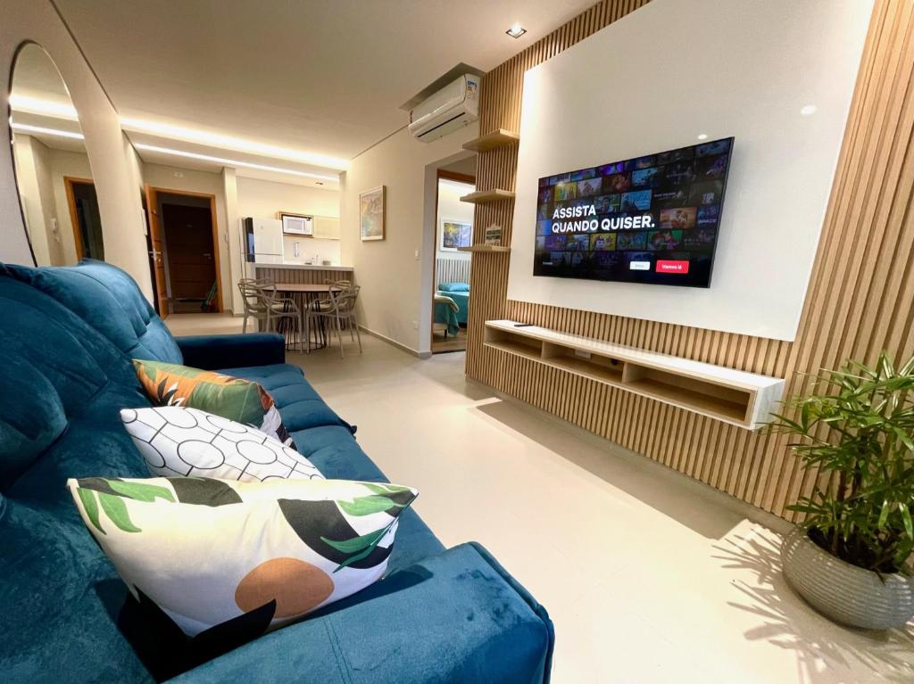 sala de estar con sofá azul y TV de pantalla plana en Condomínio Novo No Centro de Ubatuba, en Ubatuba