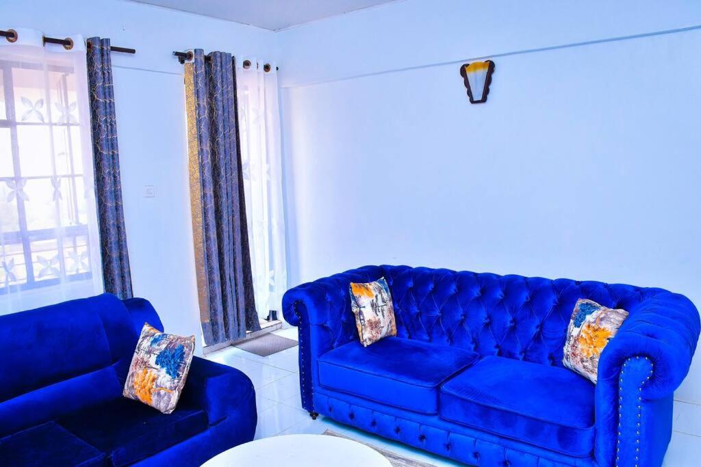 un divano blu e una sedia in soggiorno di Cozier Domicile Apartments a Maragoli