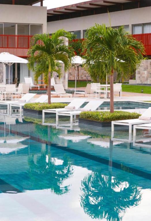 a swimming pool with palm trees and white chairs at Flat Completo - Ilê de Pipa in Pipa