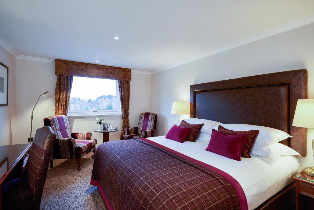 a hotel room with a bed and a desk and a window at Macdonald Highlands Hotel at Macdonald Aviemore Resort in Aviemore