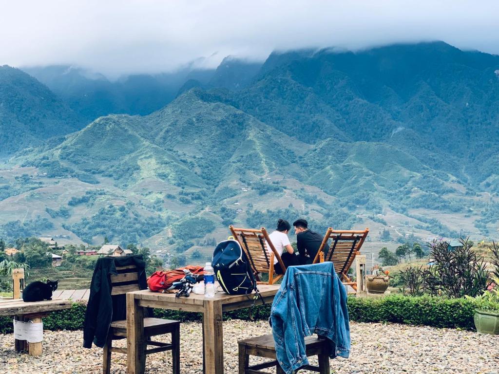 two people sitting in chairs looking at the mountains at Sapa Rosie Stilt House in Sapa